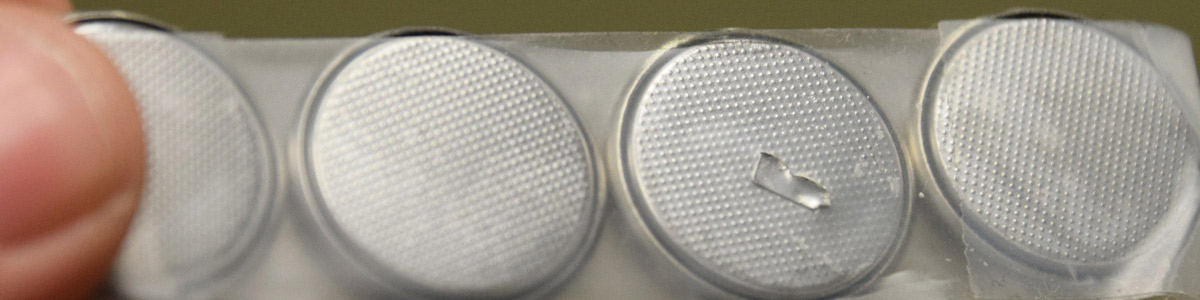 Picture of a row of lithium button batteries properly taped. Lithium button batteries should always be taped to safely store or prepare them for recycling if original packaging is unavailable.