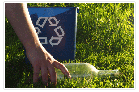 A picture of a hand picking up a bottle in front of a recycling bin. NLR wants to help businesses recycle universal waste and to educate consumers on how to recycle universal waste.